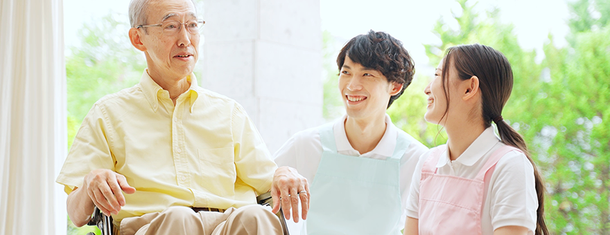 Gambar staf perempuan dan laki-laki tersenyum pada seorang pria lanjut usia