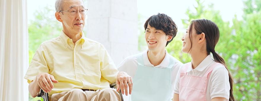 Image of a female and male staff smiling at an elderly man