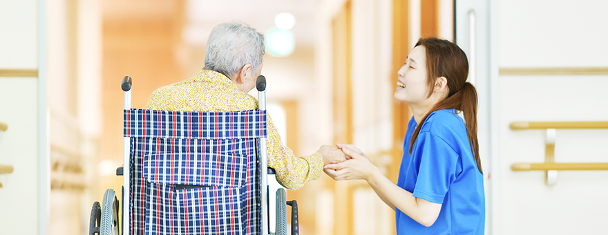 Image of a female staff chatting with an elderly woman in a wheelchair