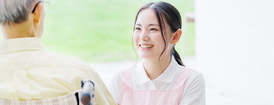 Female staff smiling at an elderly man in a wheelchair